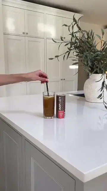 A smiling woman holding up a can of iced coffee
