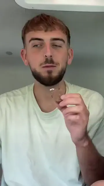 A young man holding up a piece of chocolate biscuit
